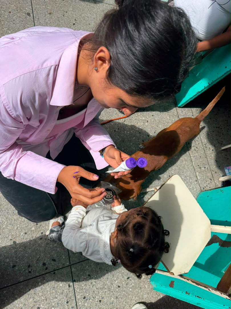 Voluntaria pintando caritas junto a una niña con su galleta